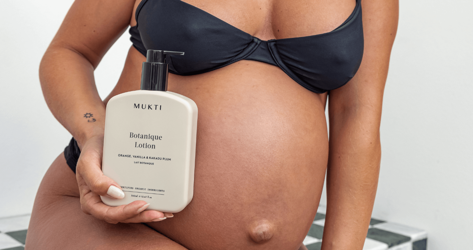 Pregnant woman holding Mukti Organics Body Lotion